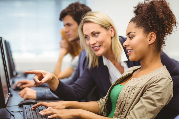 Instructor in a coding bootcamp teaching one of her students with a smile