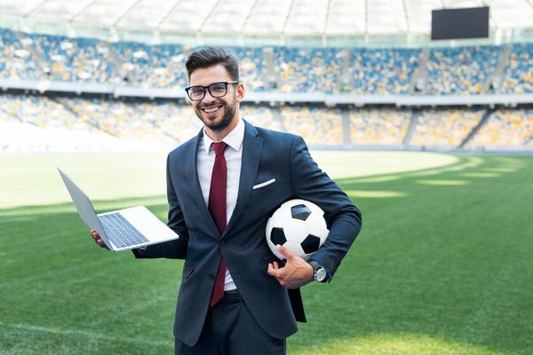 man-in-suit-and-eyeglasses-holding-a-laptop-and-football